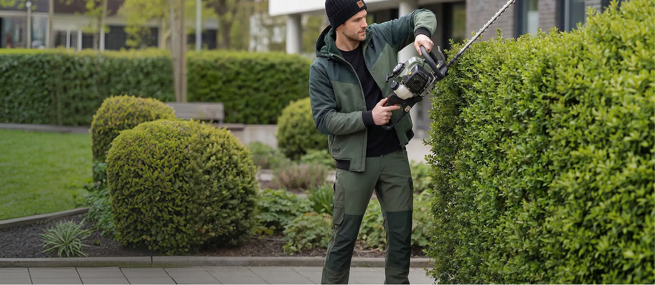 Mann in Sobral Arbeitskleidung schneidet mit der Heckenschere eine Hecke im Vorgarten
