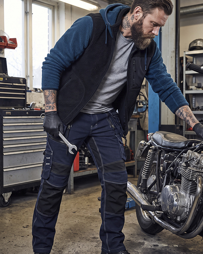 Mann in Arbeitskleidung am Motorrad in der Werkstatt